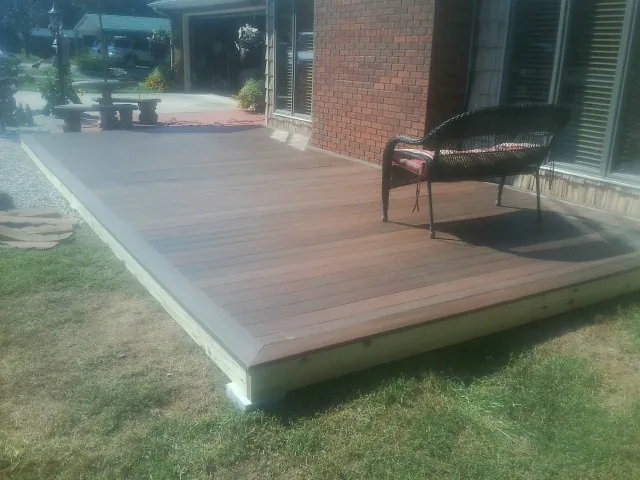 New wood deck and wicker chair beside a brick house in Freeport