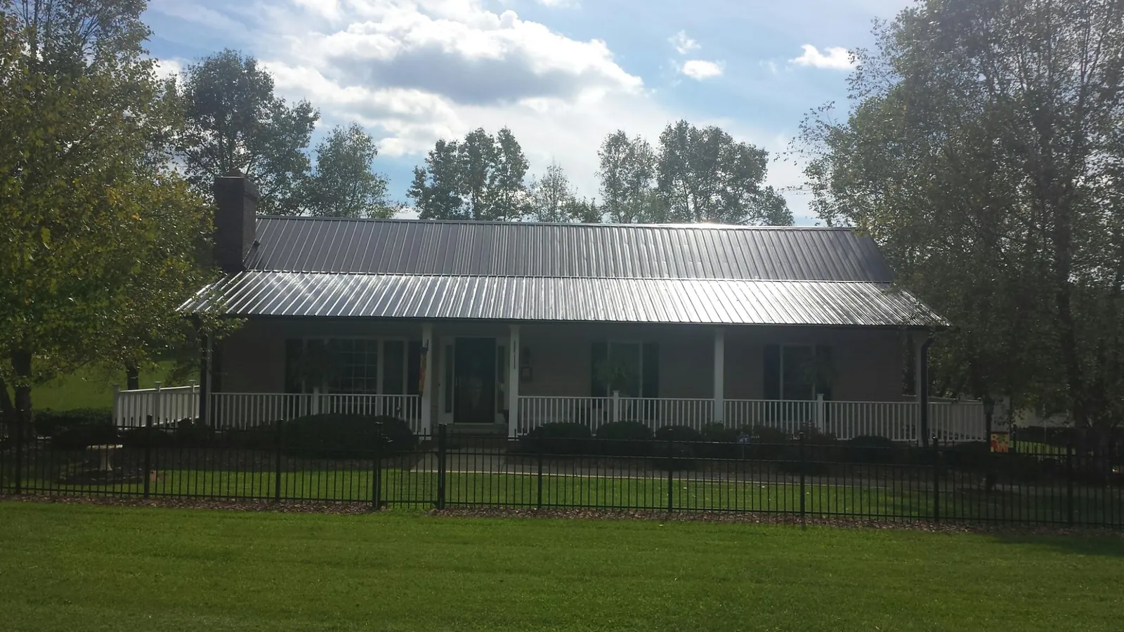 Gray metal roof on a brick ranch with a full width front porch — Gutter Guard Installation work by our crew in Freeport
